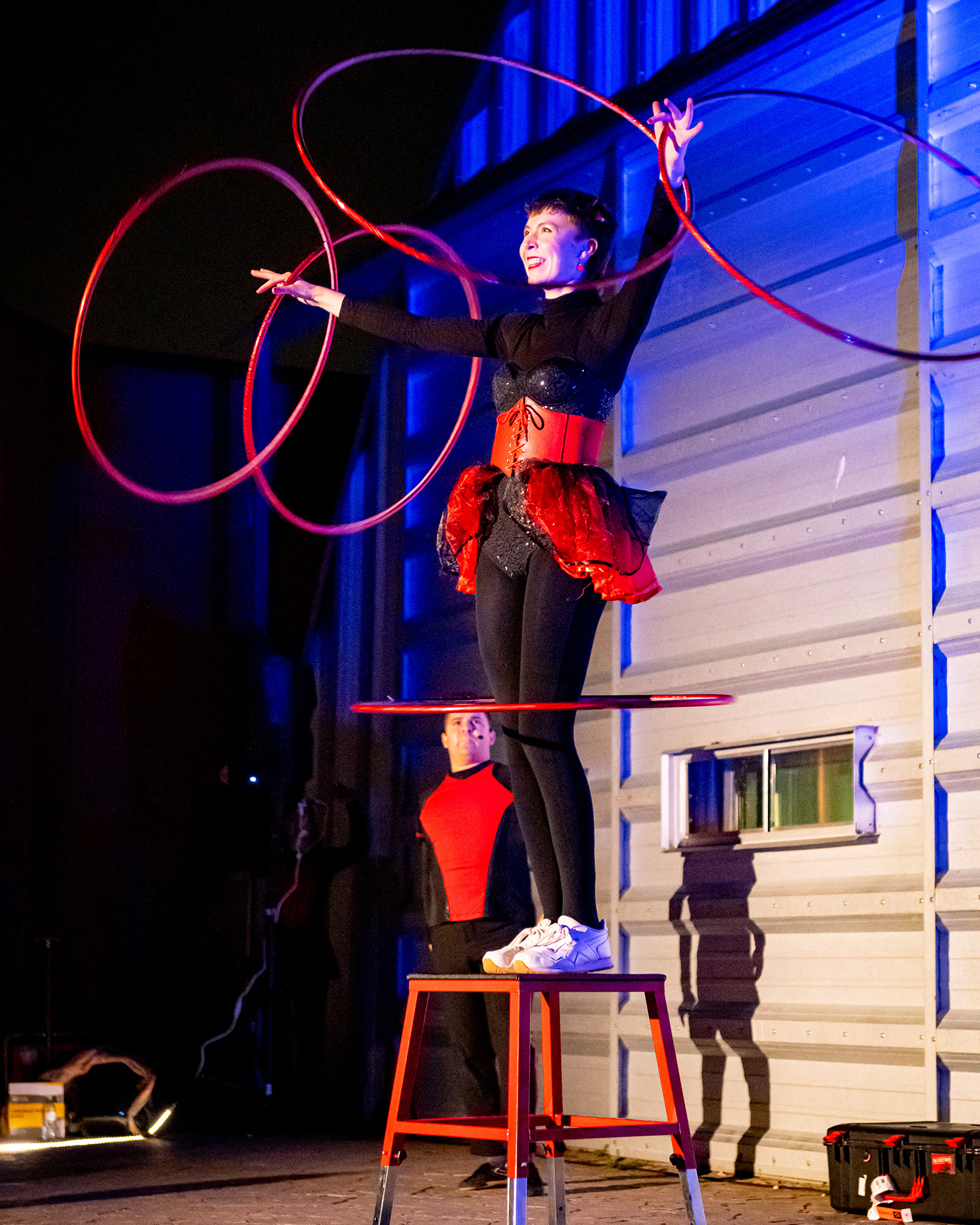 Hoop performer stands on a stool with several hoops over her head