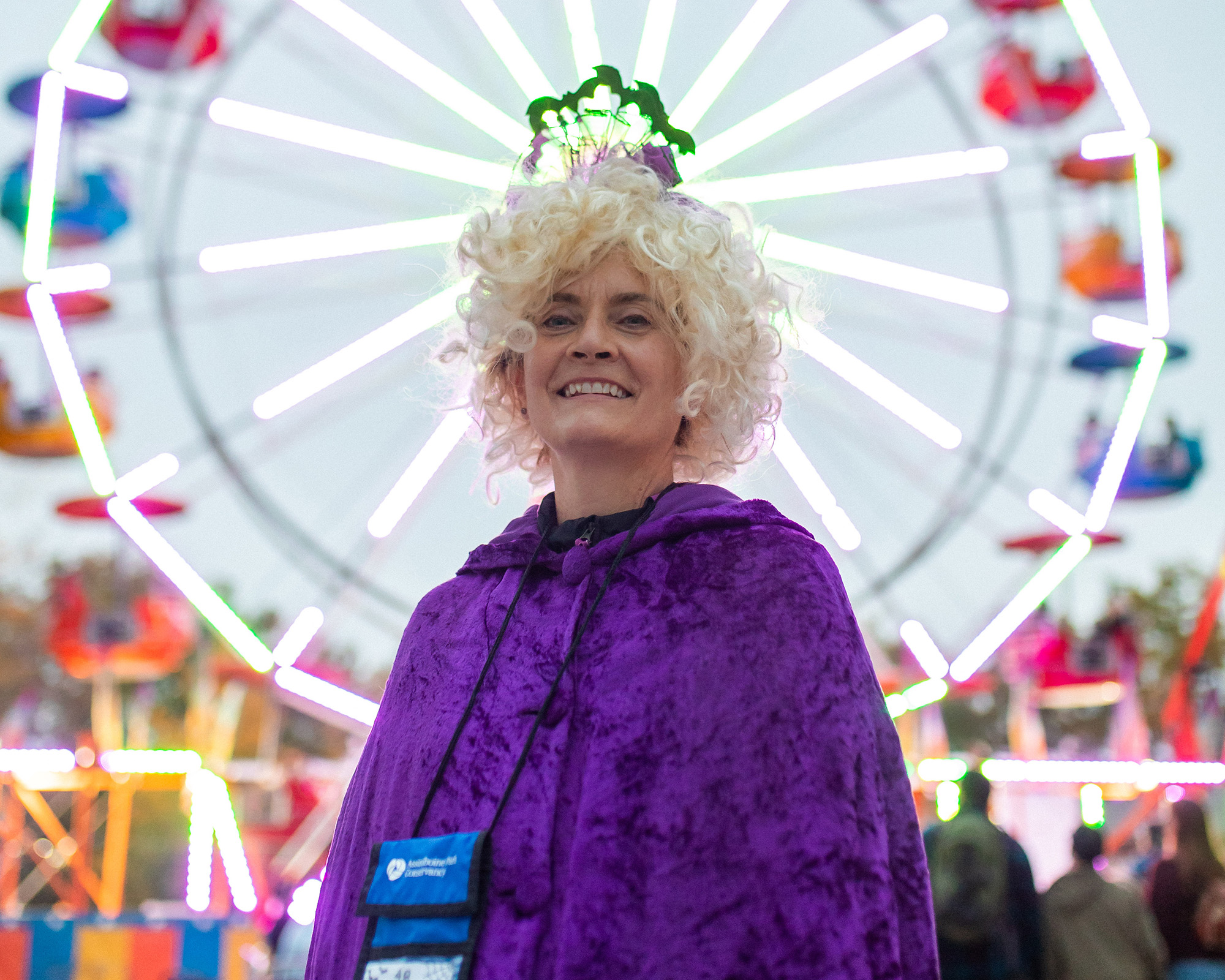 Boo at the Zoo volunteer in costume poses in front of a Ferris wheel