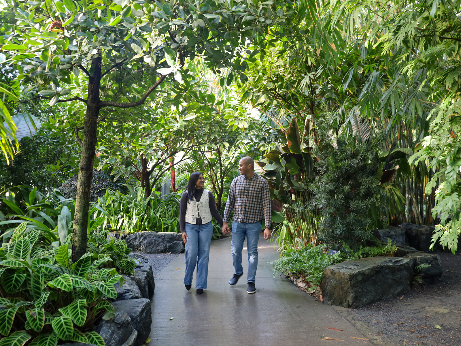A couple walks under greenery inside The Leaf