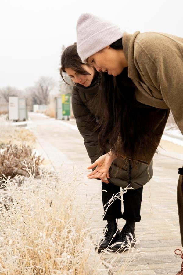 Carmen and Mamie looking at a plant in the garden