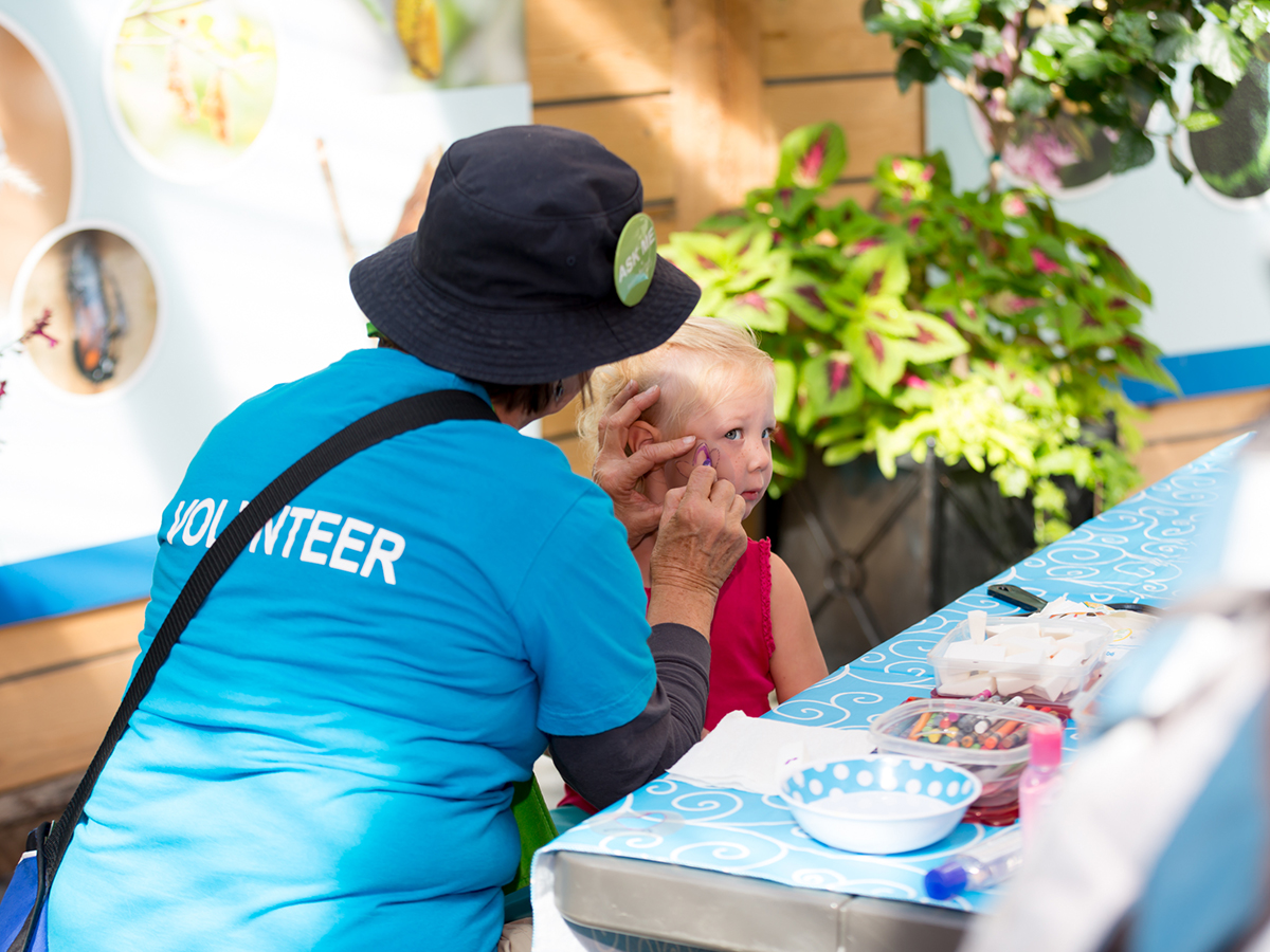 Volunteer face painting at a past Wildest Dreams event