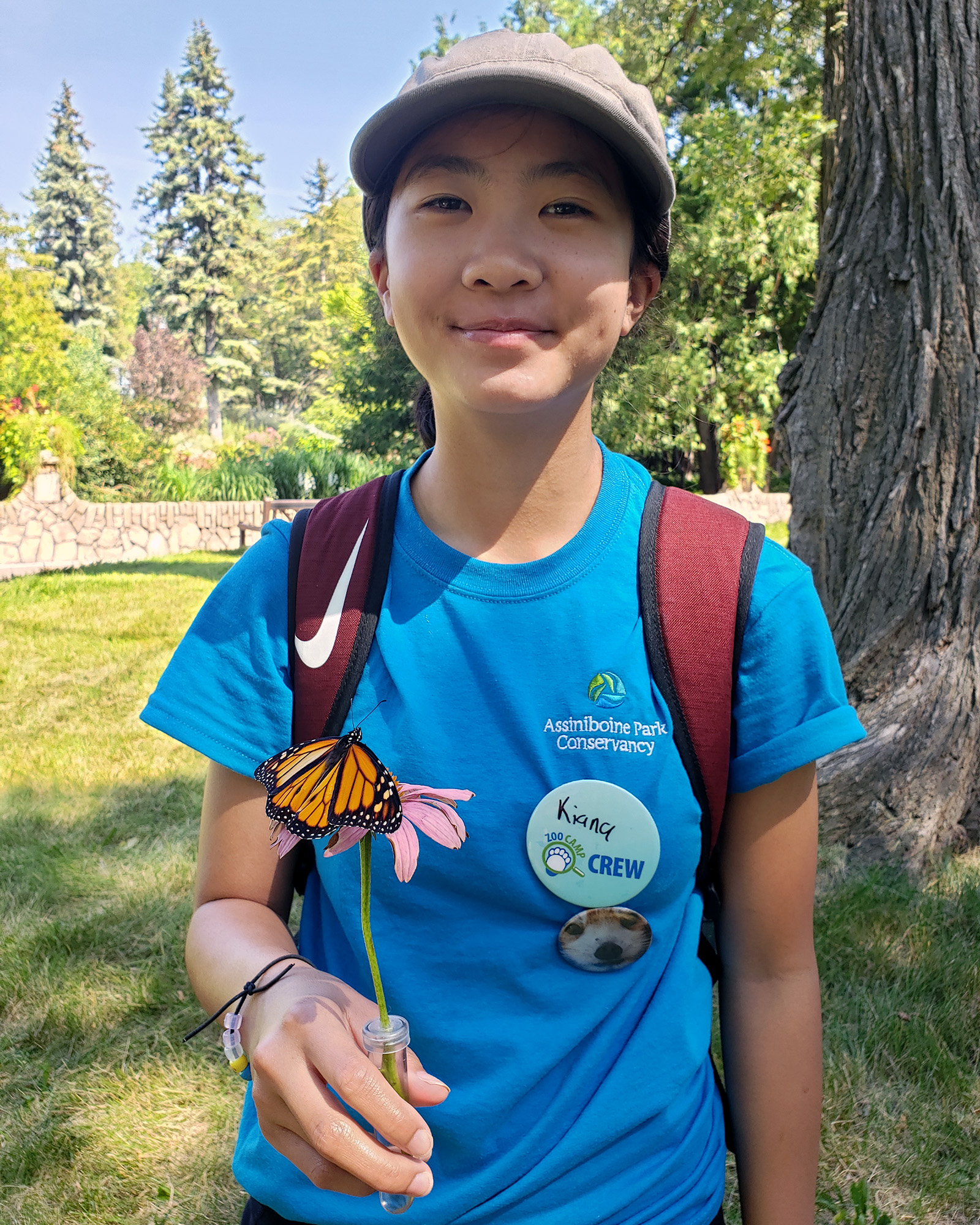 Teen Volunteer poses with a butterfly on a flower