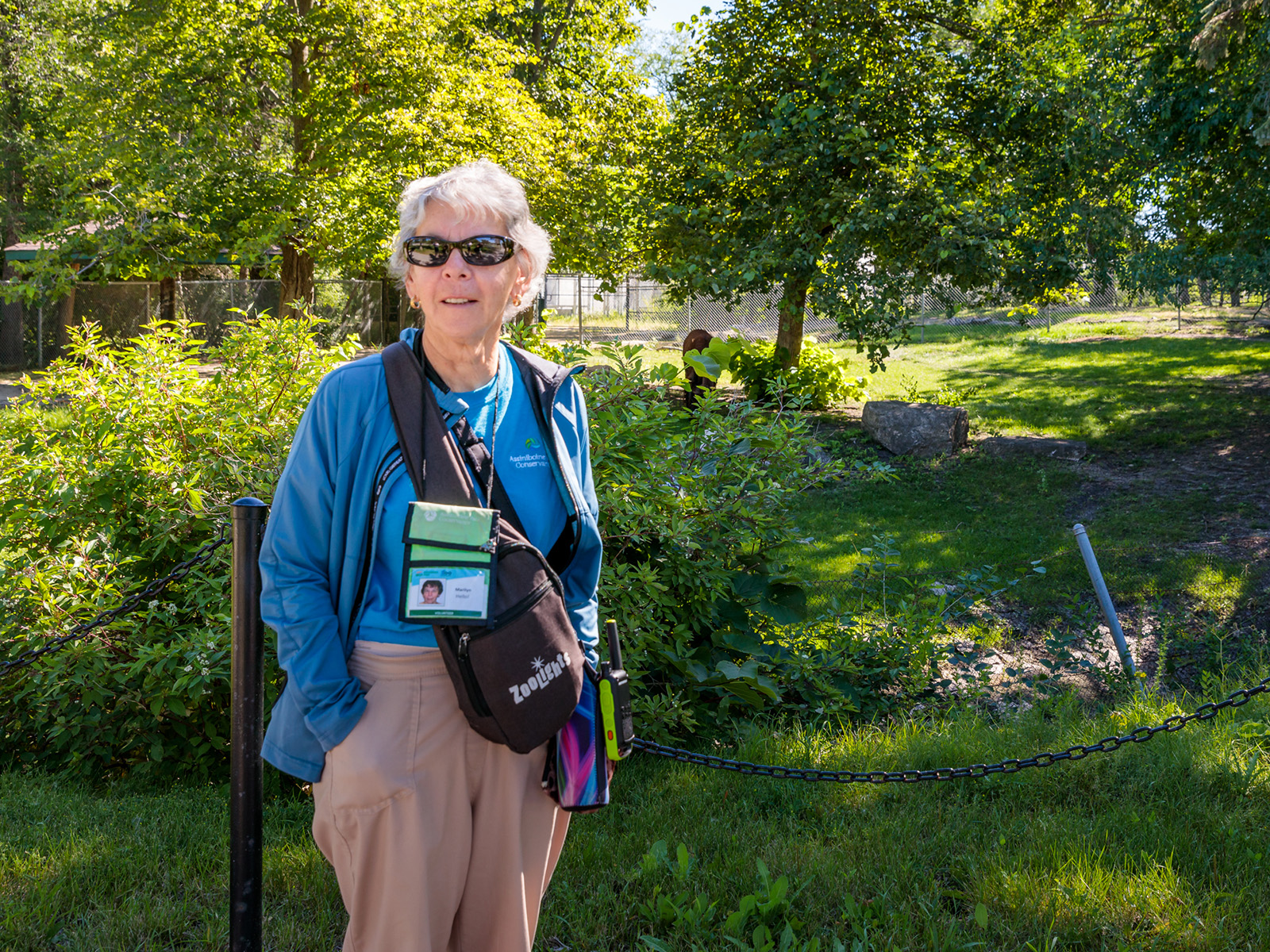 one woman in a blue volunteer shirt and jacket smiles at the camera. Located in the Zoo. 