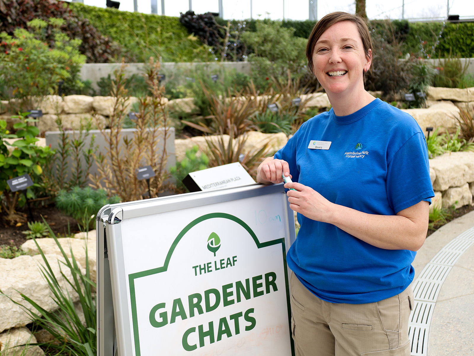 Gardener stands in front of a gardener chat sign